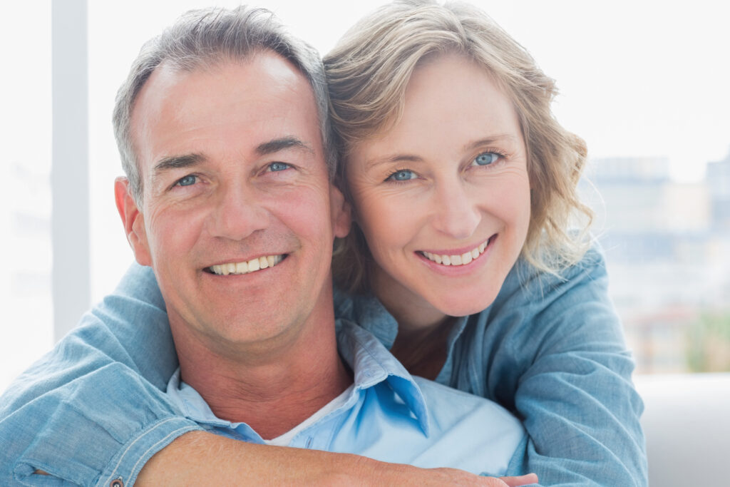 Smiling woman hugging her husband on the couch from behind