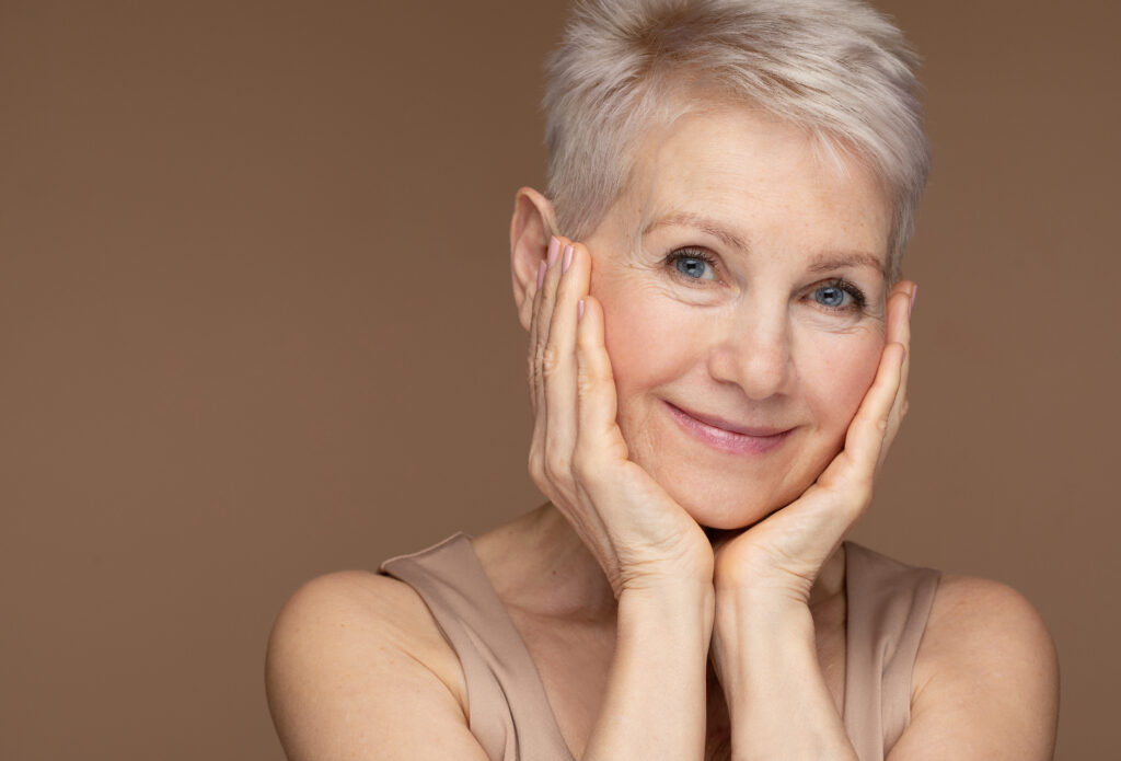 Beauty portrait of mature woman smiling with hand on face.
